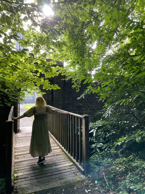Michelle walking onto a wooden bridge in the woods at Ashford Castle